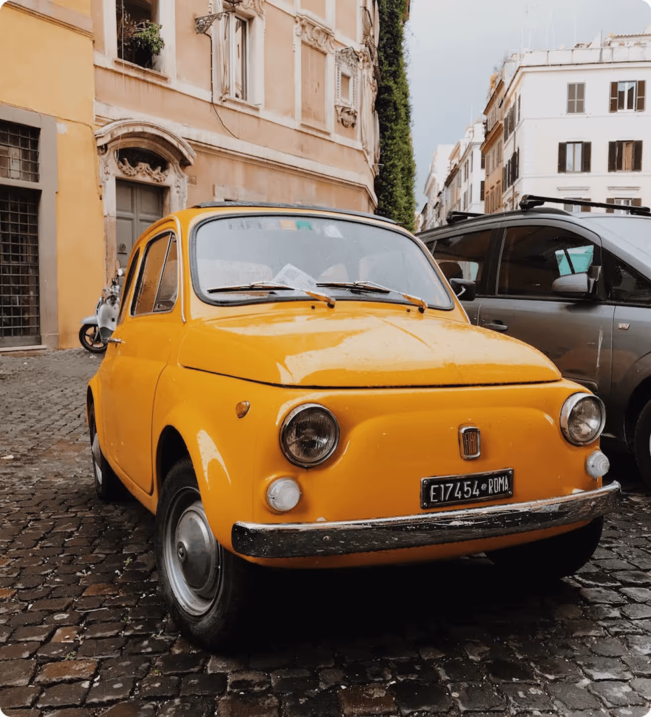 A small yellow car parked on a cobblestone street.