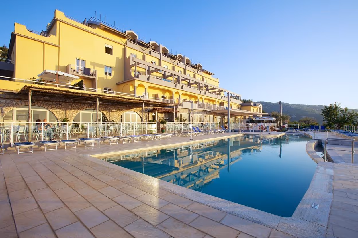 A hotel with a swimming pool in front of it.