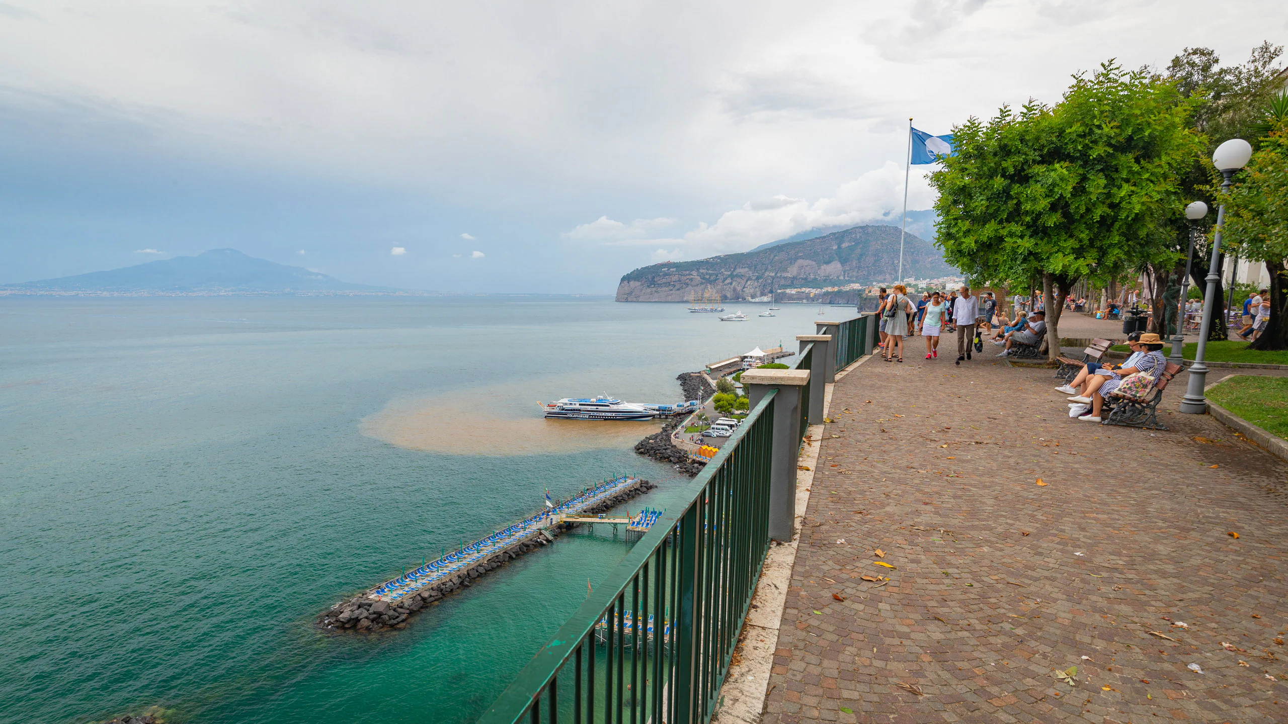 A group of people sitting on a bench next to a body of water.