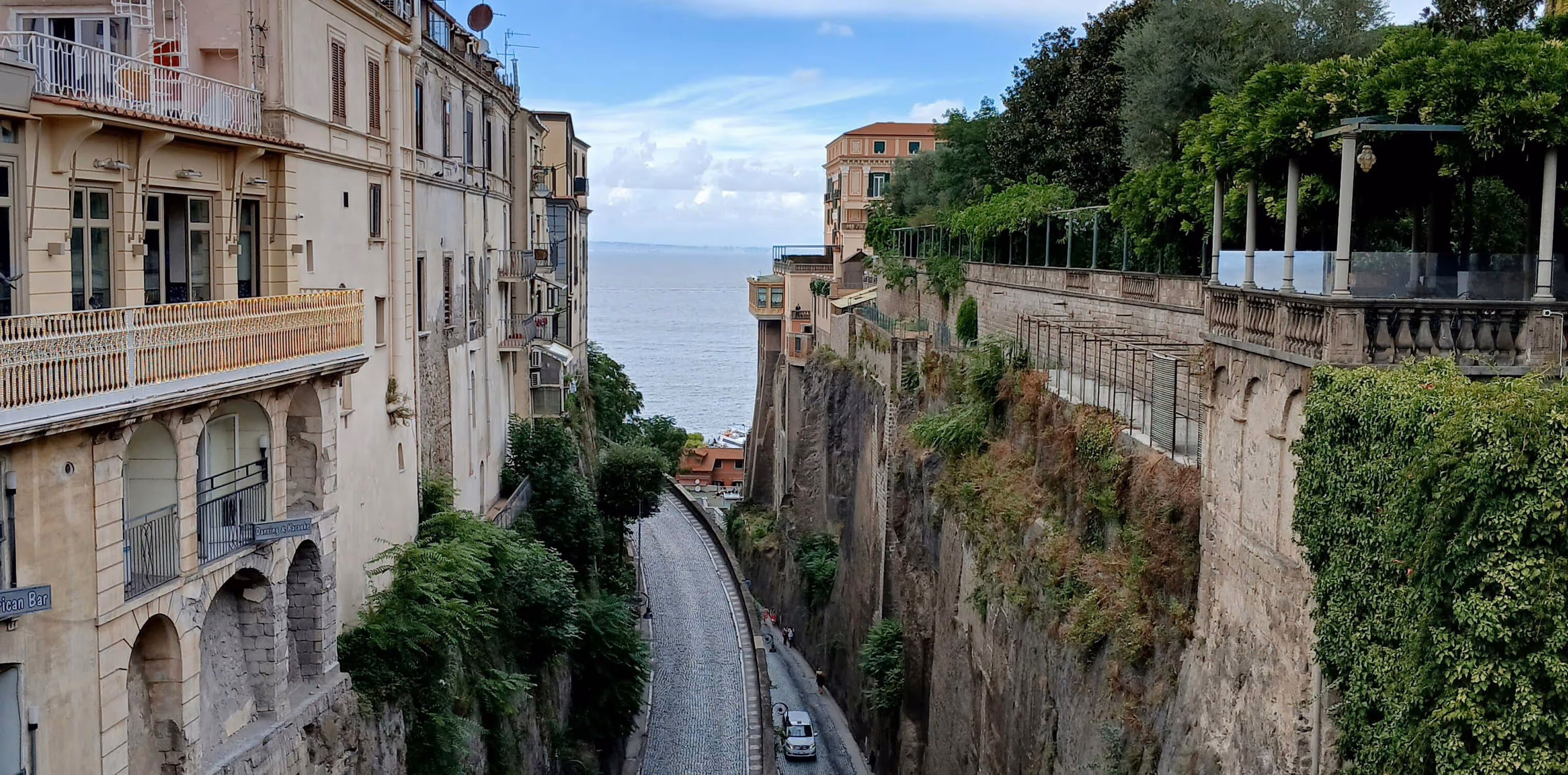 A car driving down a narrow street next to tall buildings.