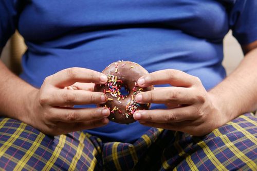 A person holding a donut representing the rising concern of ultra processed food consumption