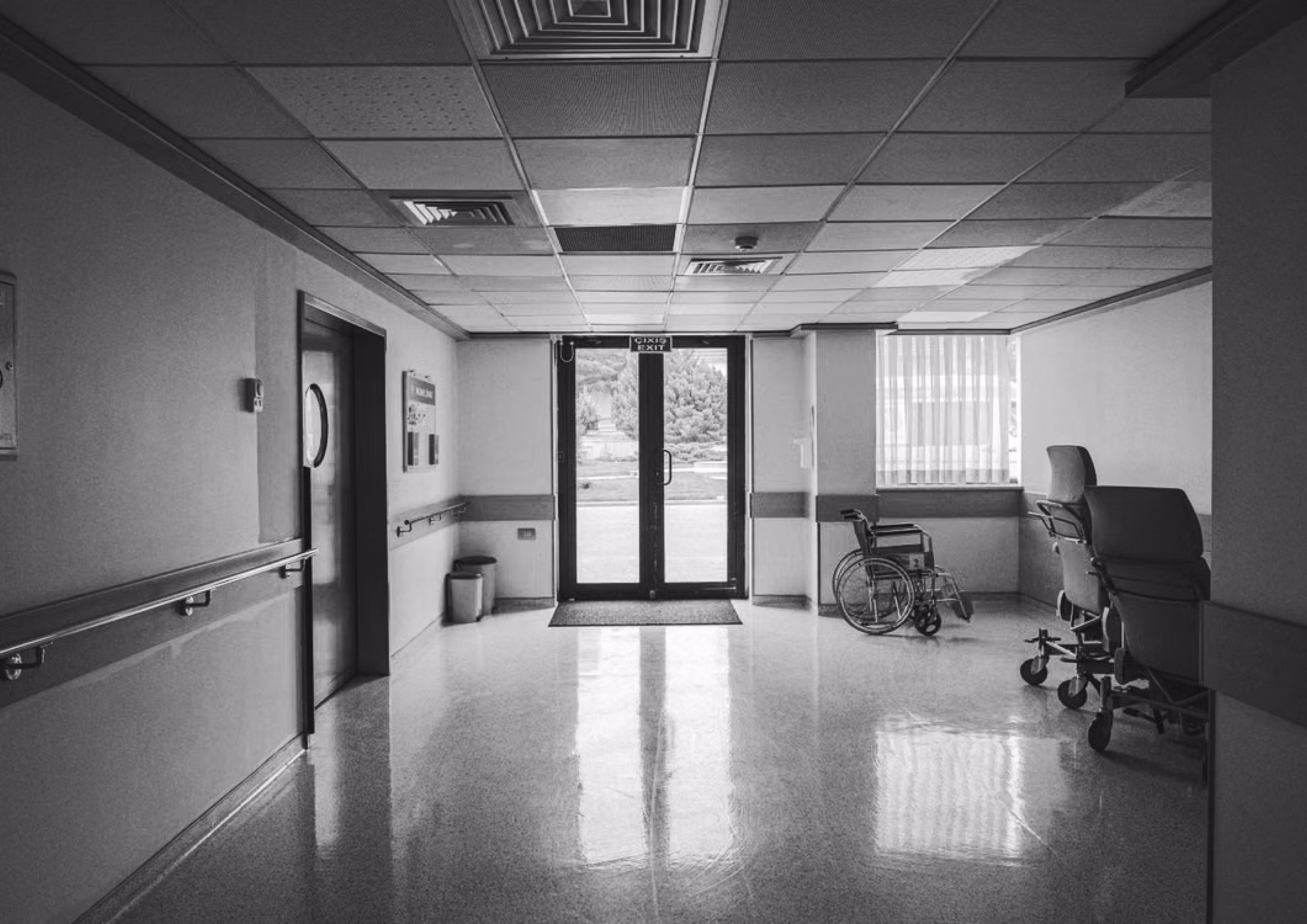 Empty skilled nursing facility hallway with a wheelchair near the entrance.