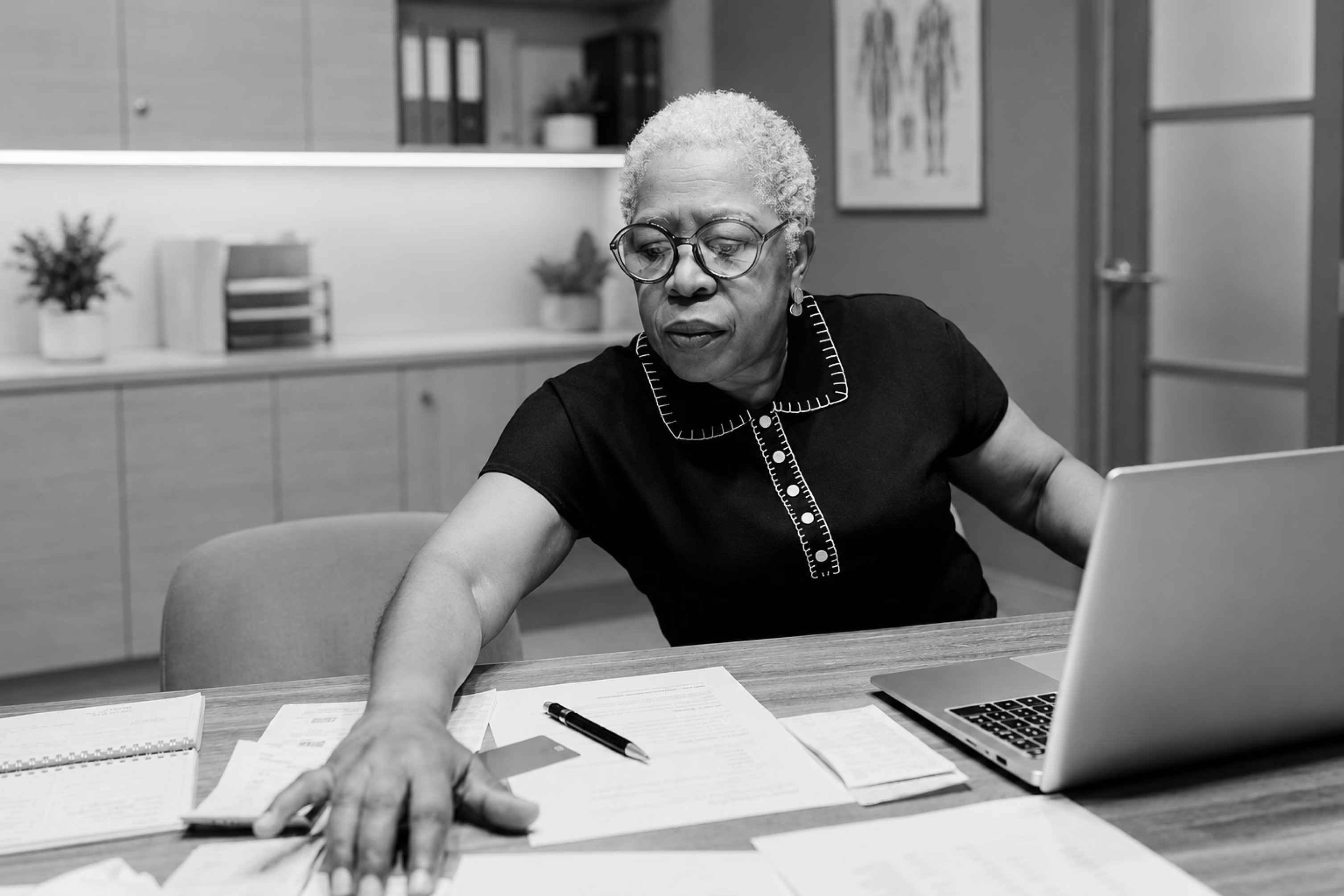 Skilled nursing leader reviewing documents and data at her desk.