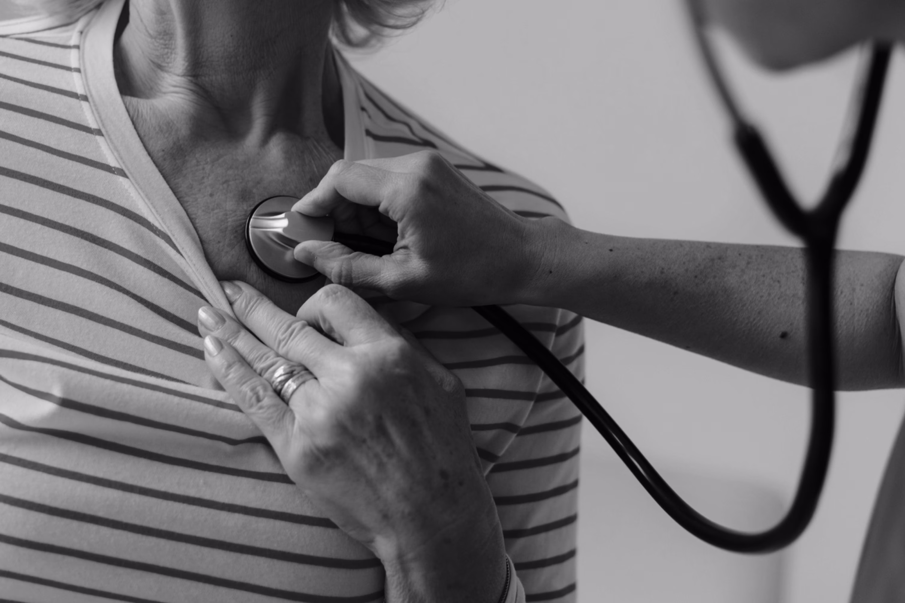 Healthcare professional listening to a patient’s heart with a stethoscope.