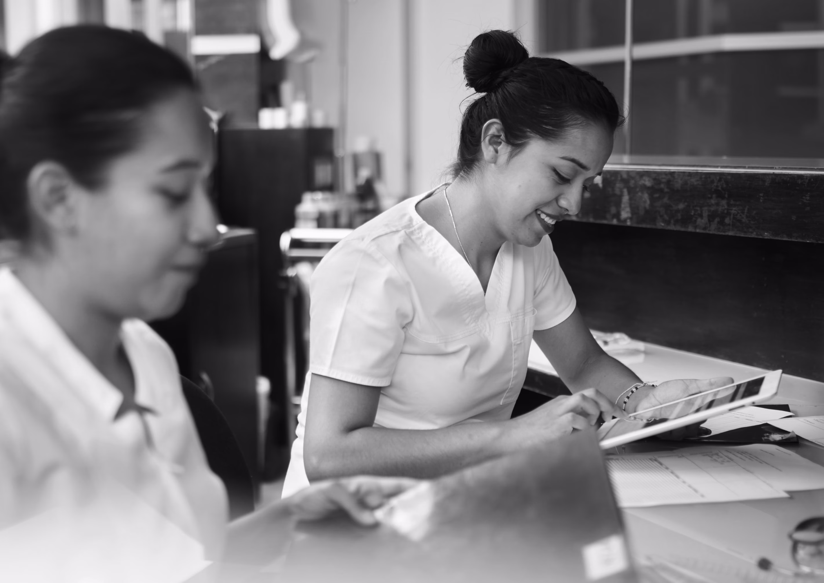 Two skilled nursing professionals reviewing patient information at a nurses’ station.