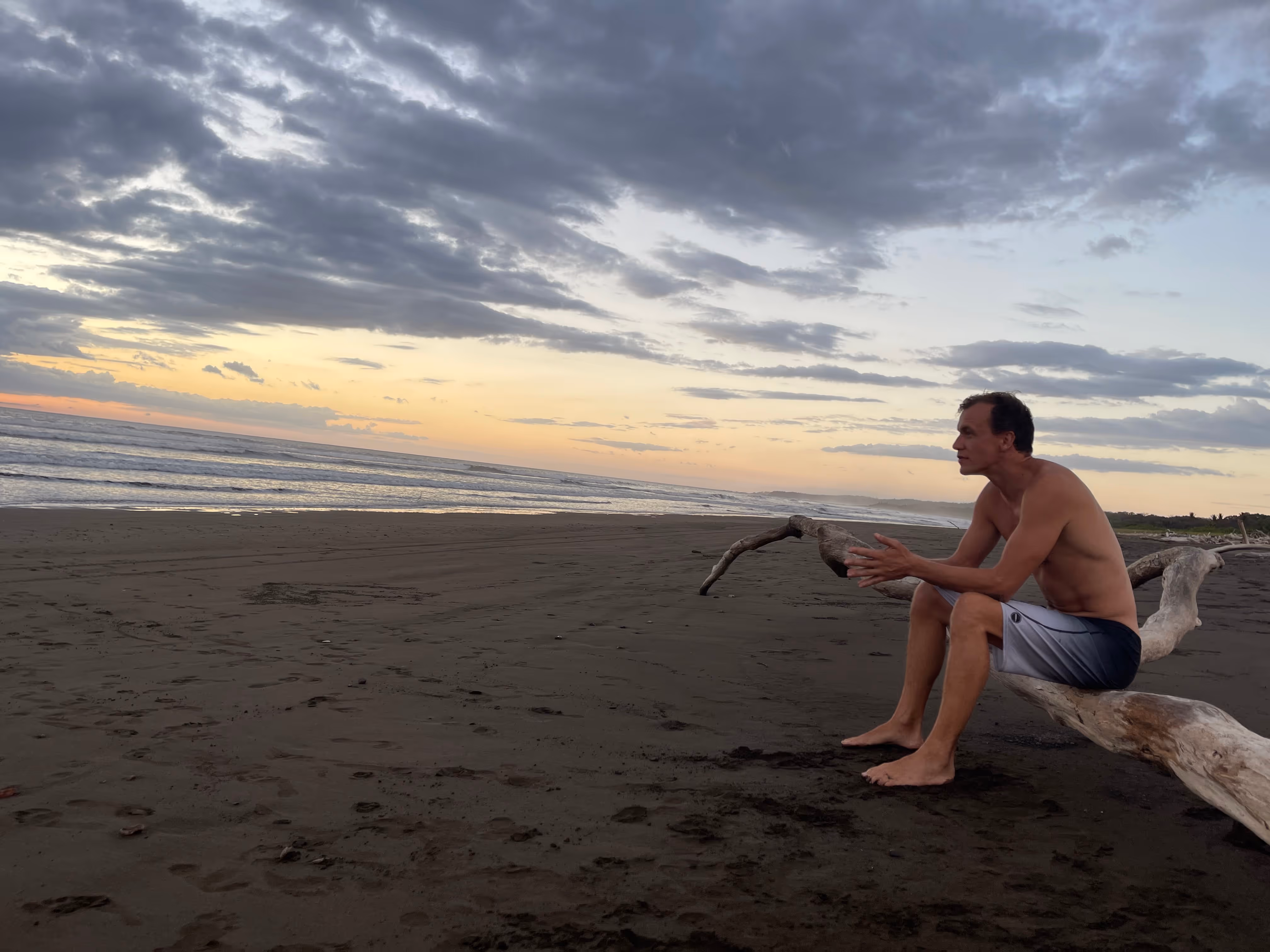 Leon sitting on a log on the beach