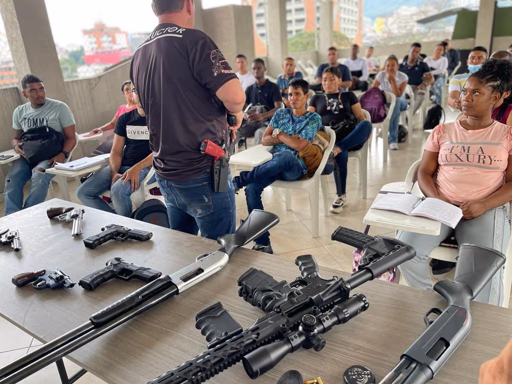 Instructor de tiro dando clase a personas de vigilancia con armamento de demostración