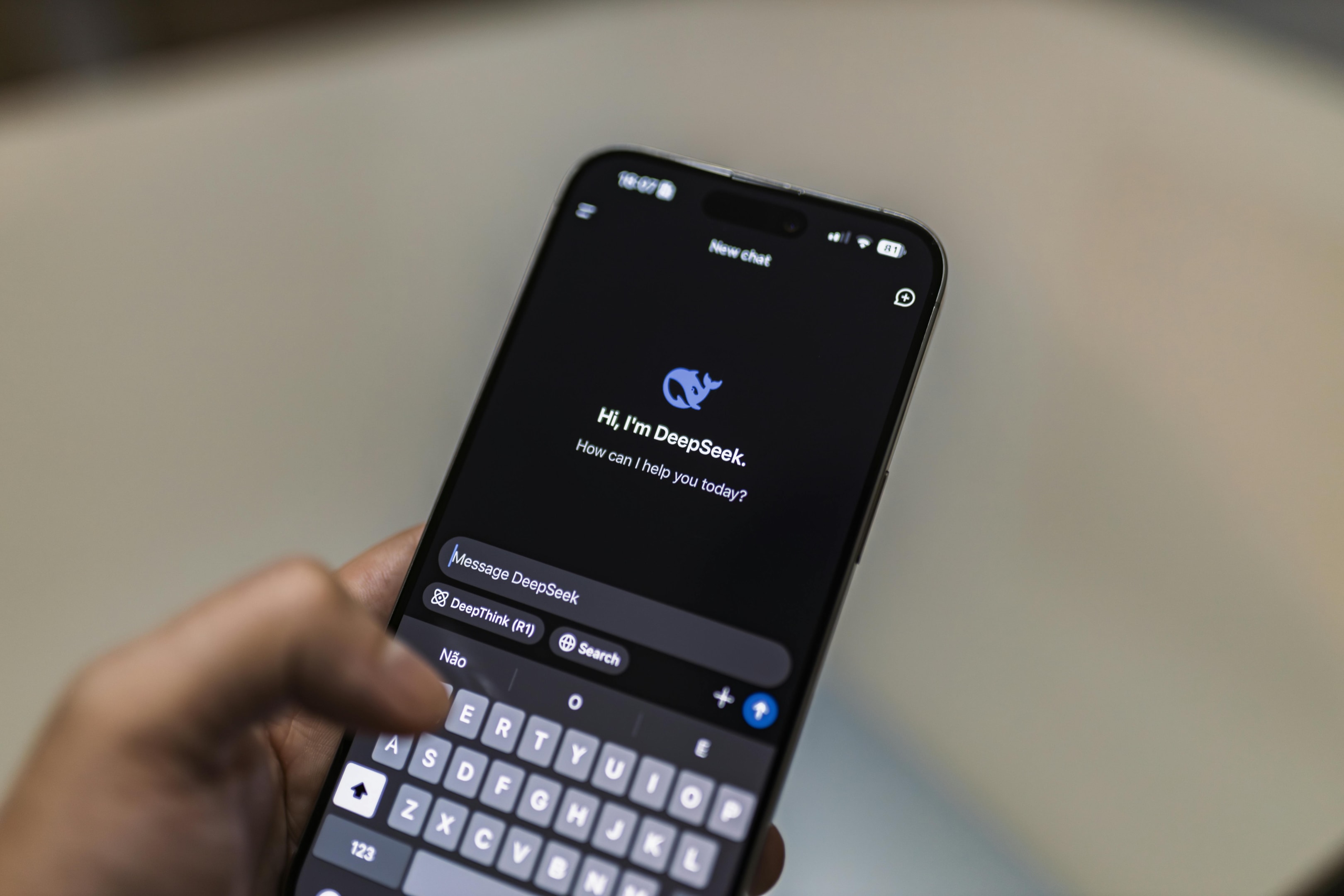 Someone holding a phone, typing a prompt to an AI chatbot.