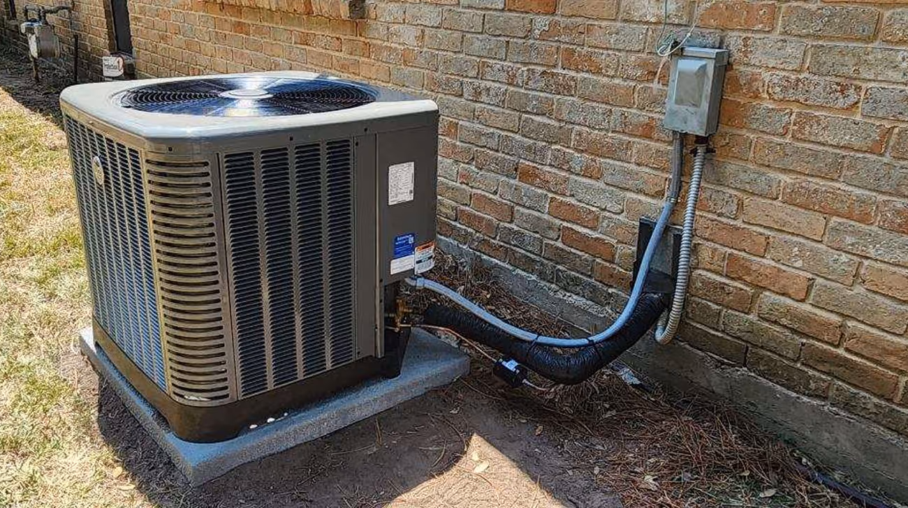 Air conditioning unit outside brick house with connected electrical wiring