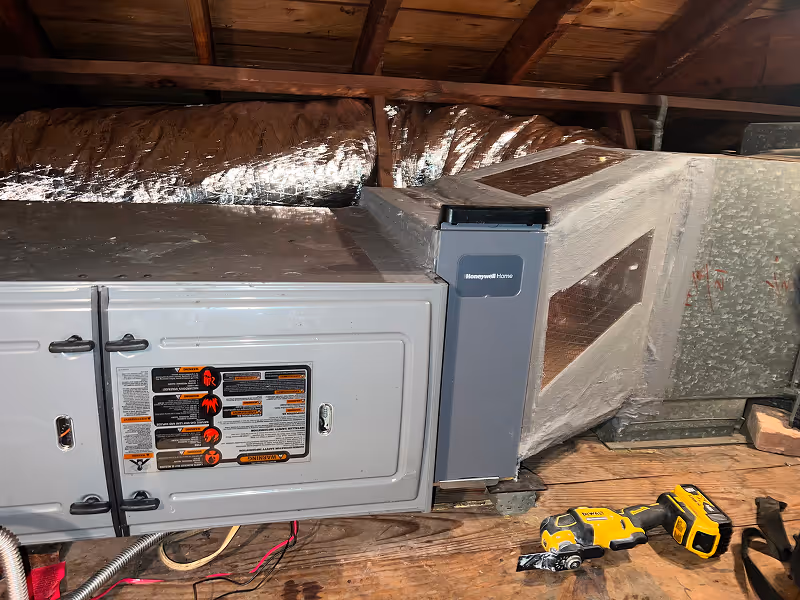 HVAC system installation in wooden attic with insulation and power tools