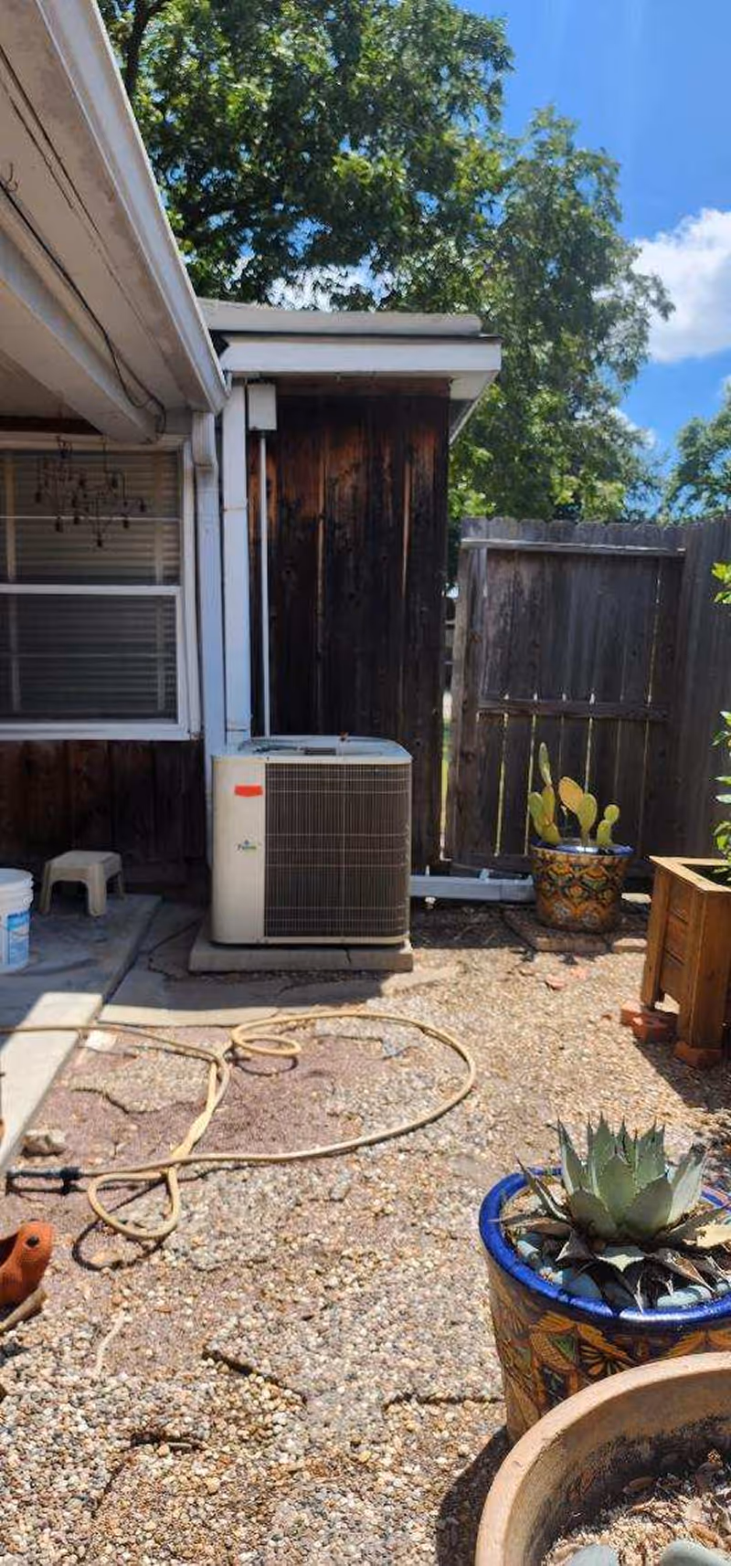 Backyard with air conditioning unit, potted succulents, and gravel ground