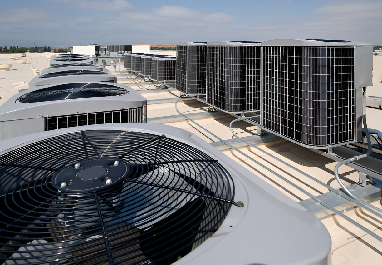 Multiple air conditioning units on a flat commercial roof on a sunny day