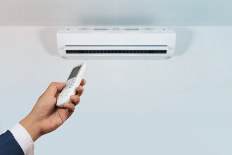 Hand holding remote of AC to adjust temperature