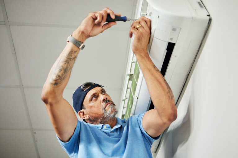 Worker in blue shirt installing or repairing something on a white wall