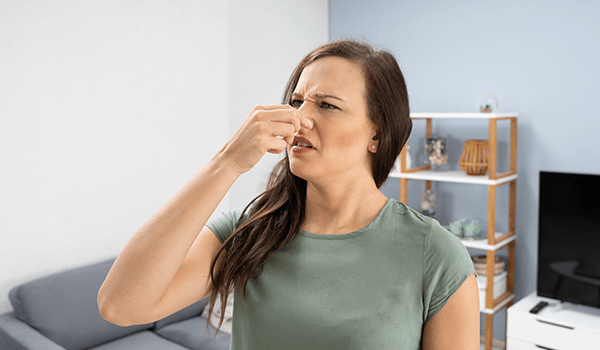 Female holding nose and trying to prevent from smelling bad air