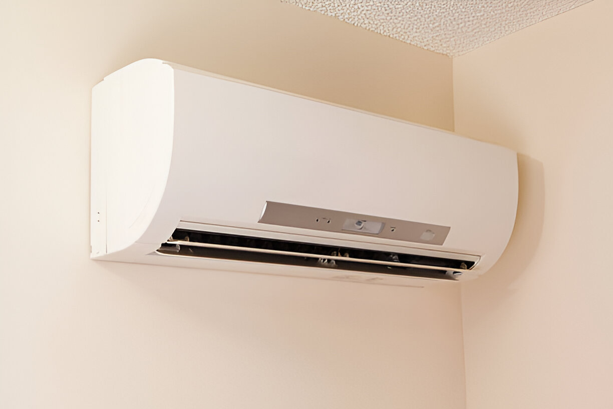 White wall-mounted air conditioning unit in corner of room