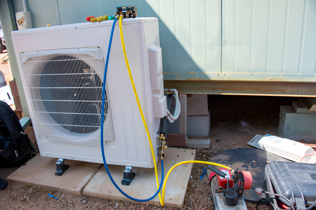 HVAC technician installing outdoor air conditioning unit with colored cables