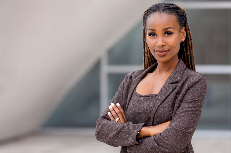 Portrait d'une femme confiante en costume brun, debout les bras croisés