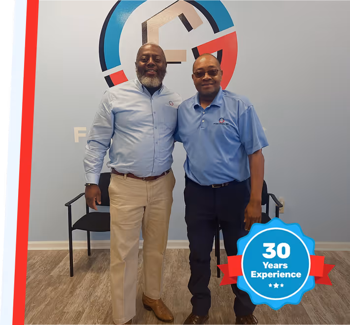 Two colleagues posing in blue shirts with 30 years experience badge