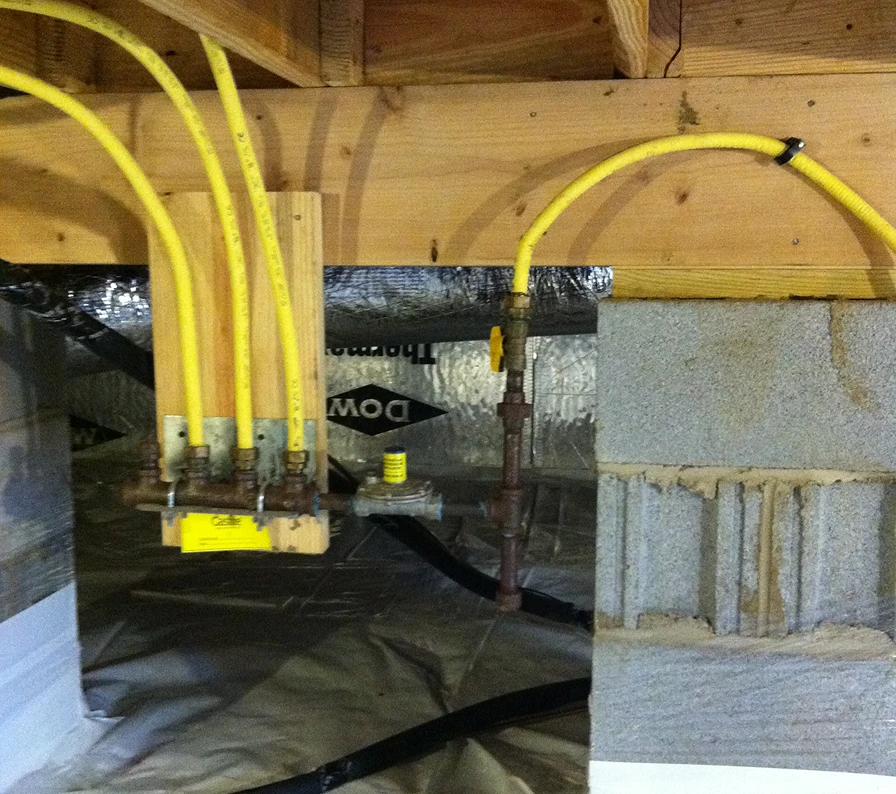 Yellow gas pipes connected in basement with wooden beams and concrete wall