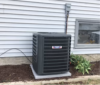 Air conditioning unit installed outside house near window and landscaping