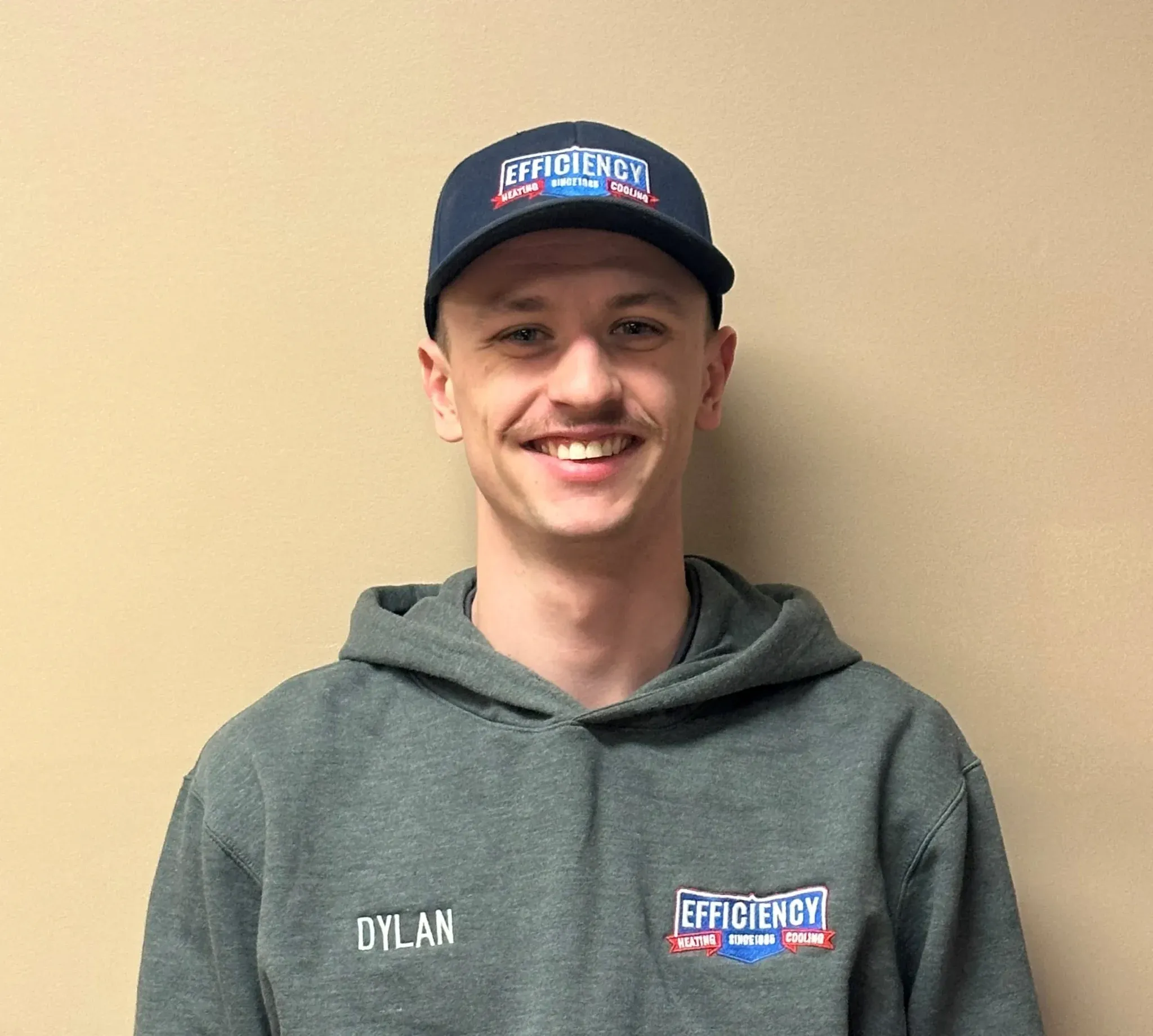 Smiling employee in green hoodie and Efficiency company cap