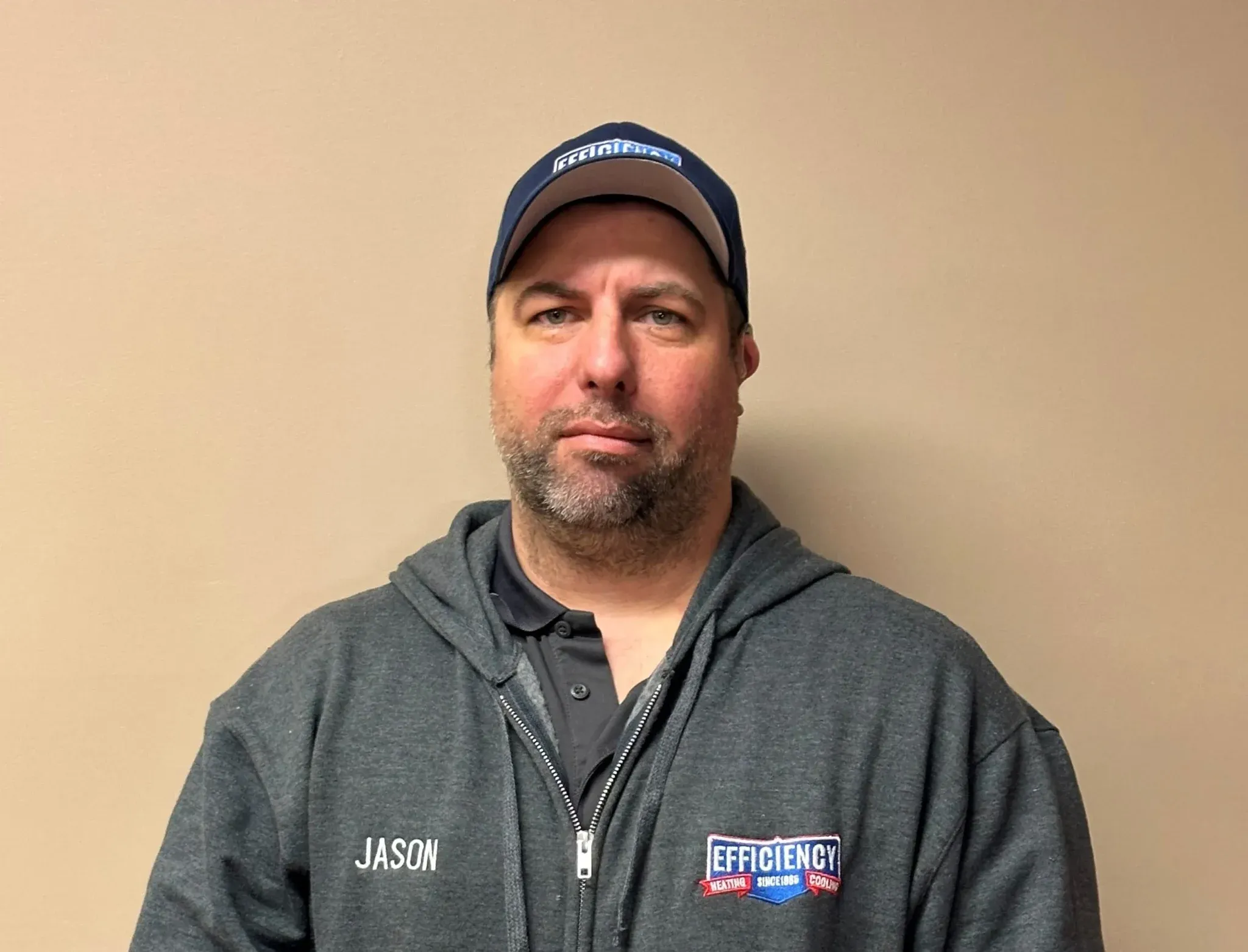 Employee in gray hoodie and cap with Efficiency Heating and Air logo