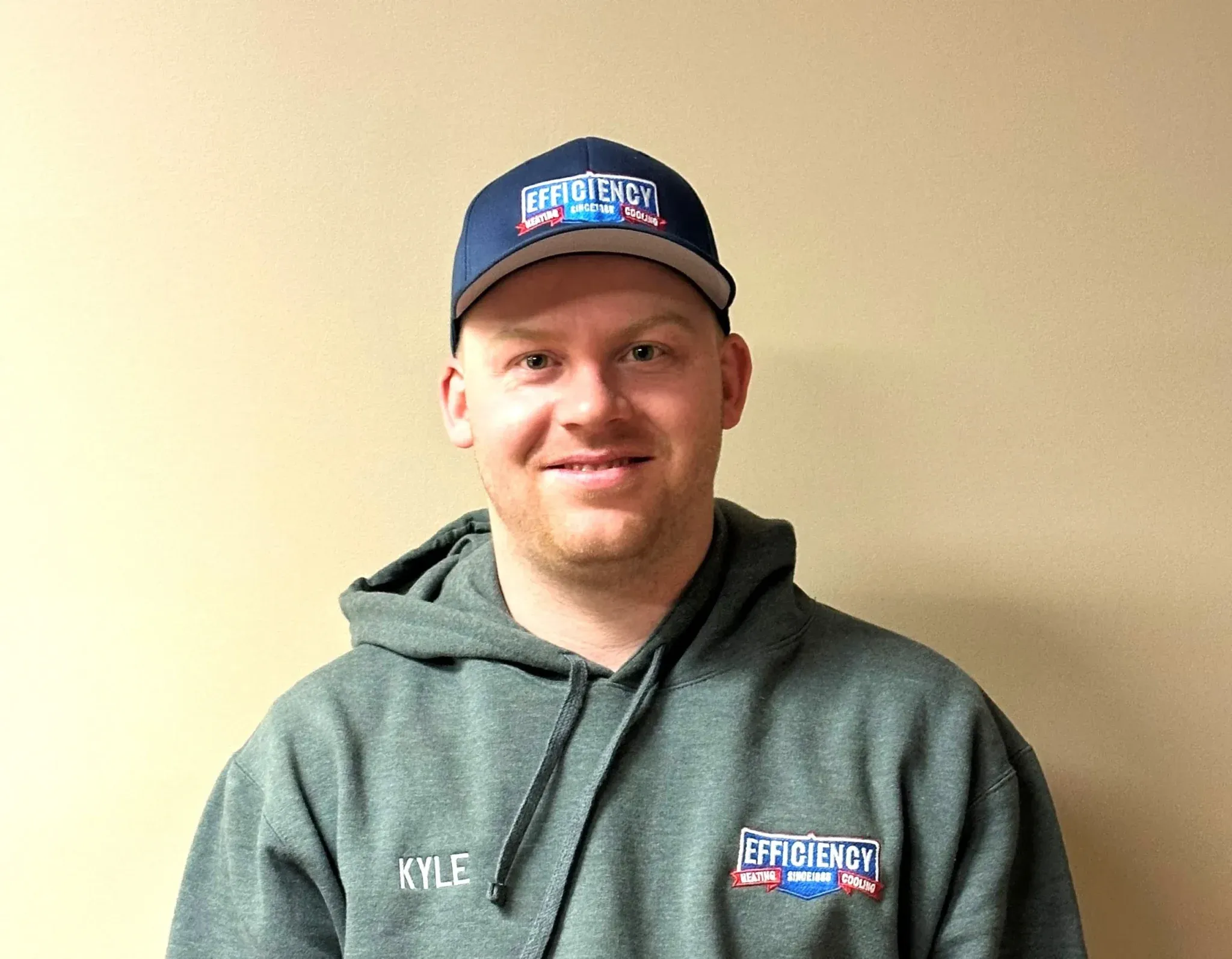 Smiling employee in green hoodie and Efficiency cap