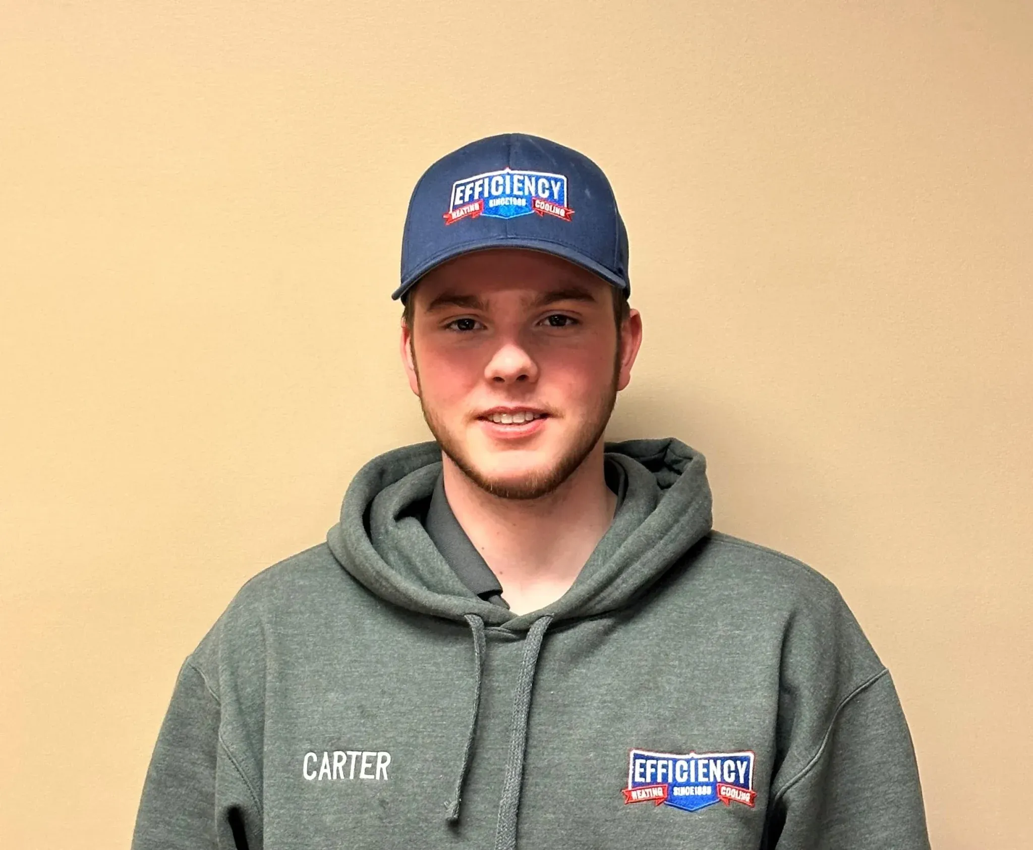 Smiling employee in gray hoodie and blue Efficiency cap