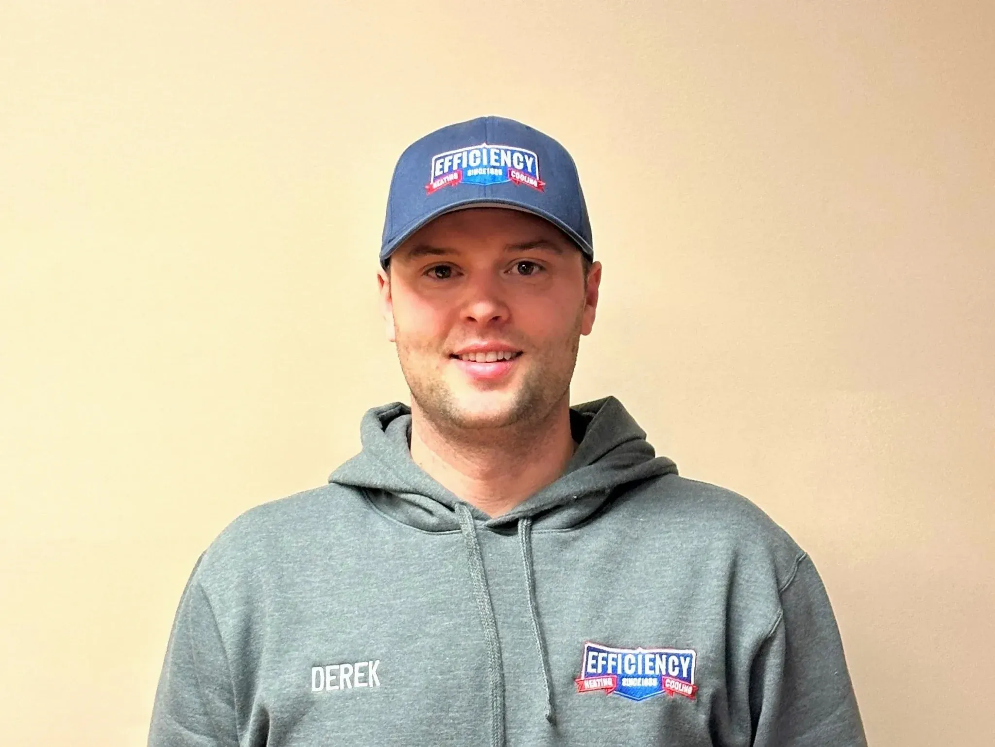 Smiling employee in gray hoodie and blue Efficiency cap