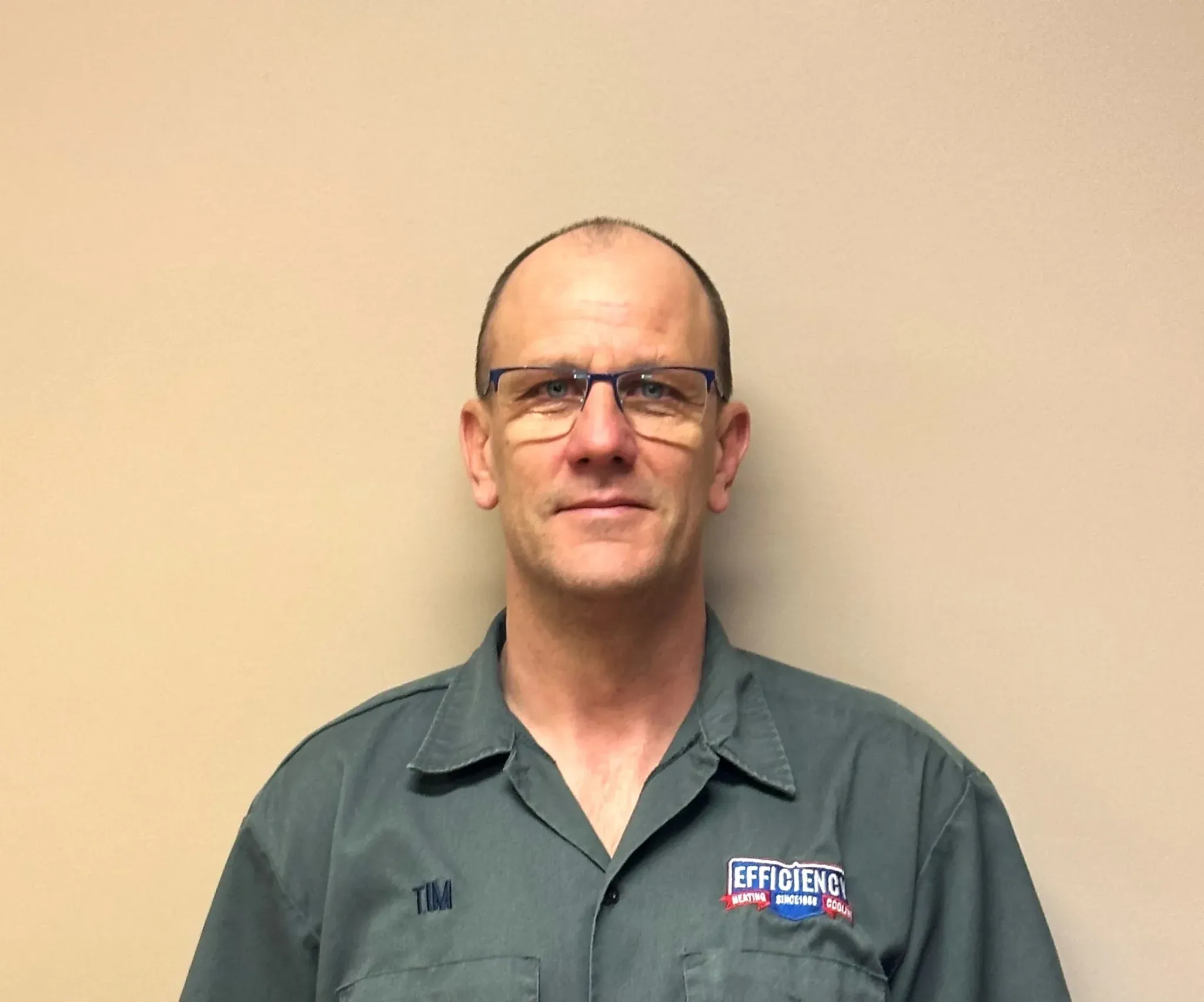 Employee wearing glasses and work shirt with Efficiency logo