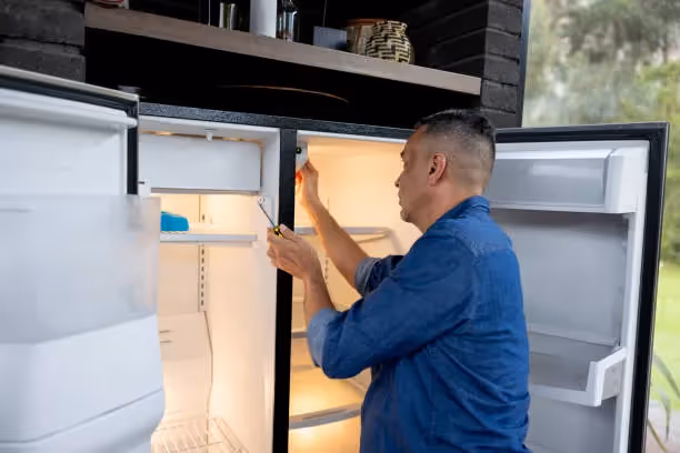 Person in blue shirt checking inside an open refrigerator