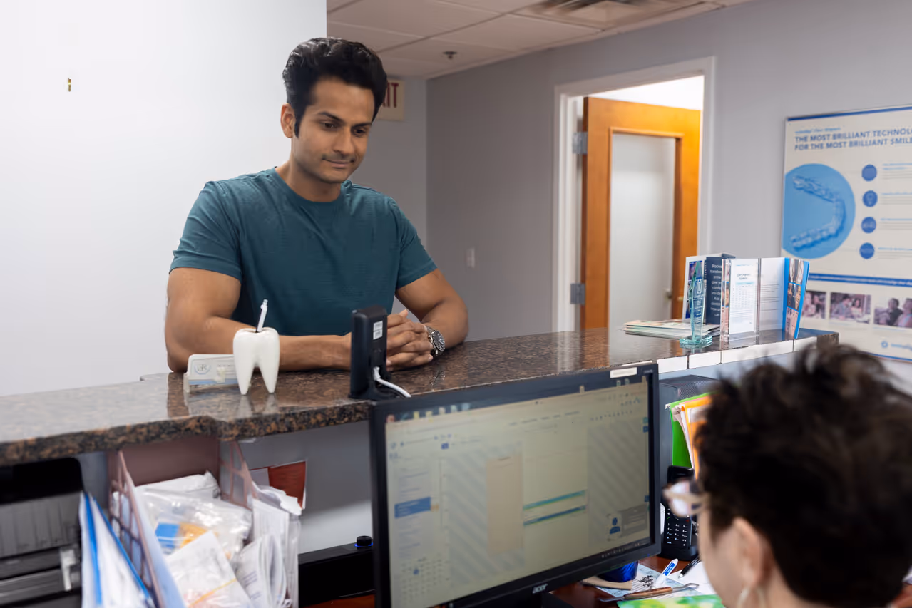 Man sitting at a dental office reception desk.