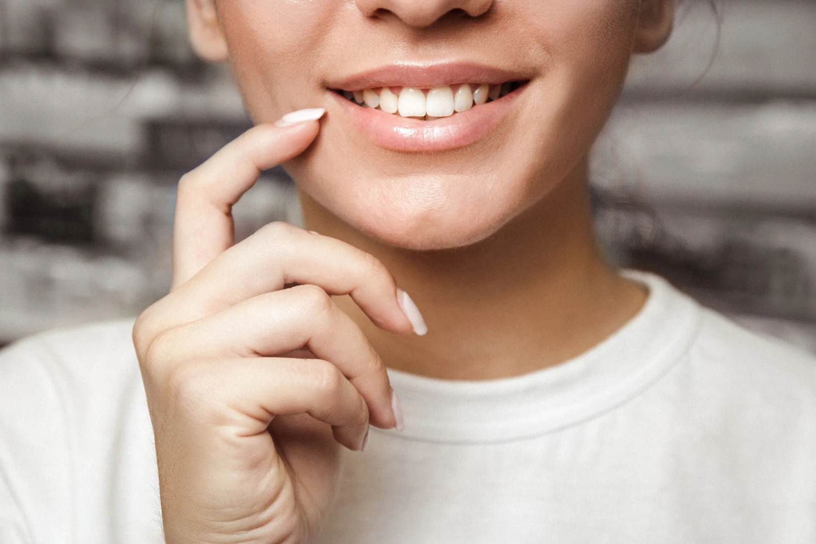 Woman smiling and pointing to her teeth with her finger.