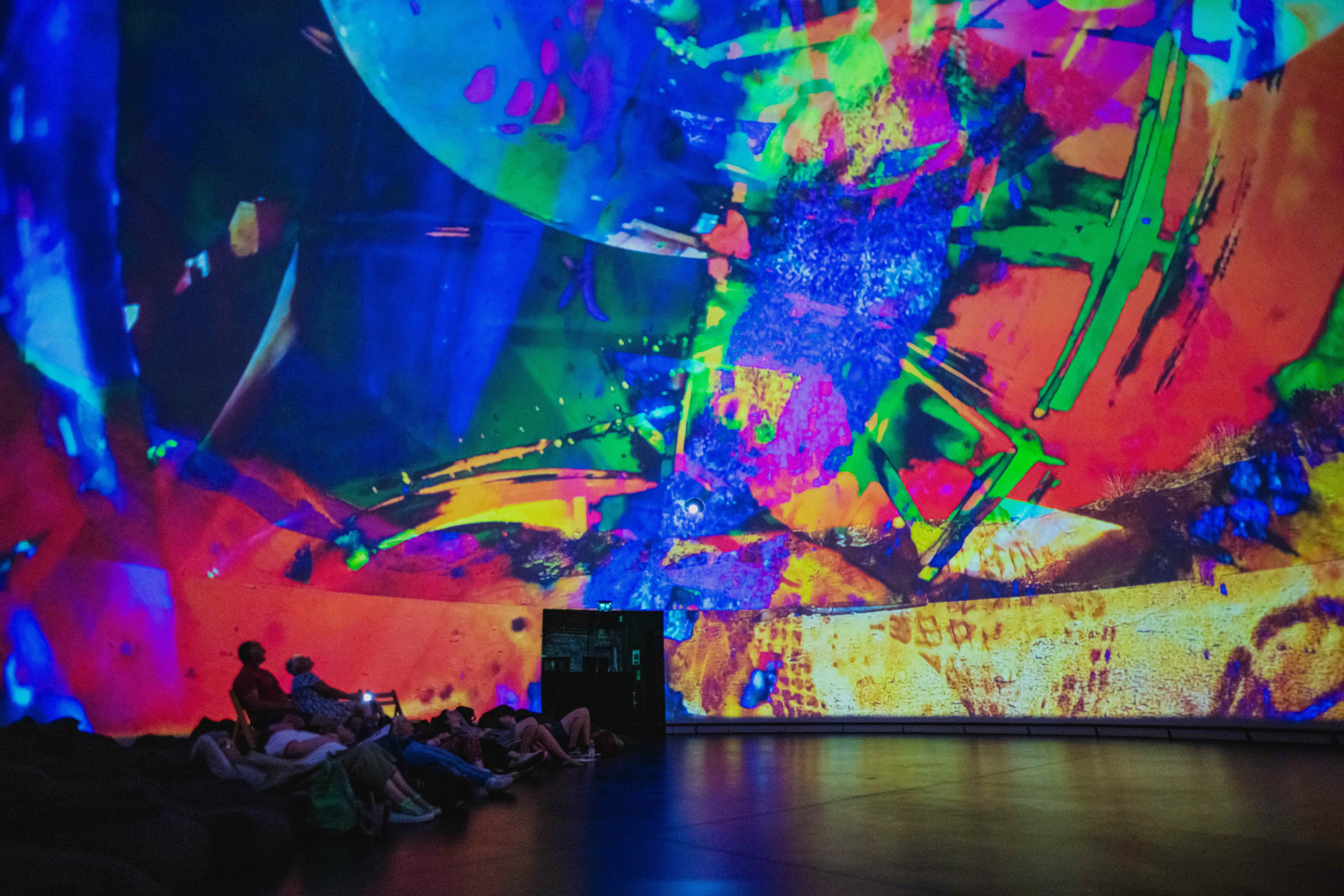photo of a 360 cinema with people sitting on beanbags with a multi colour abstract film playing around them