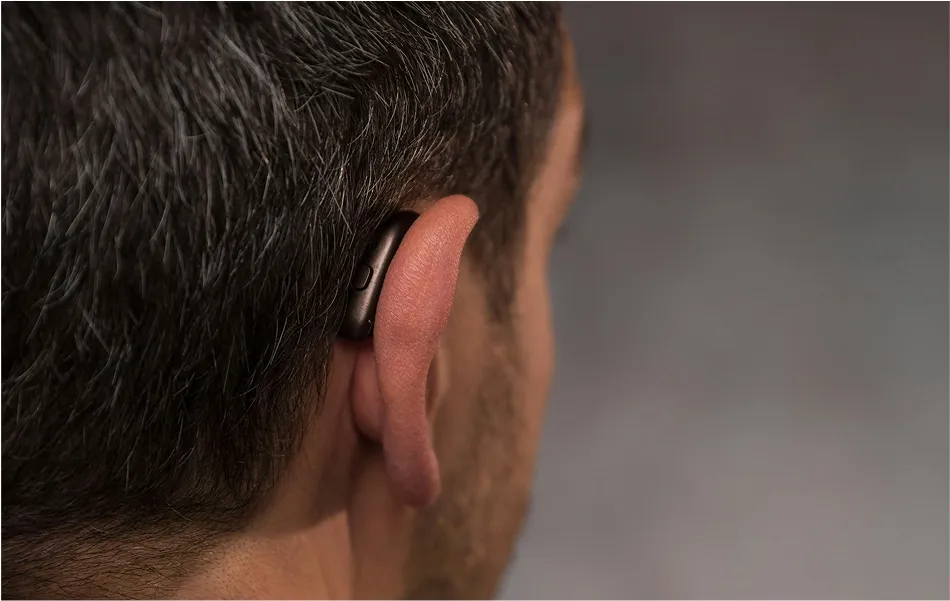 Close-up rear view of person wearing behind-the-ear hearing aid."