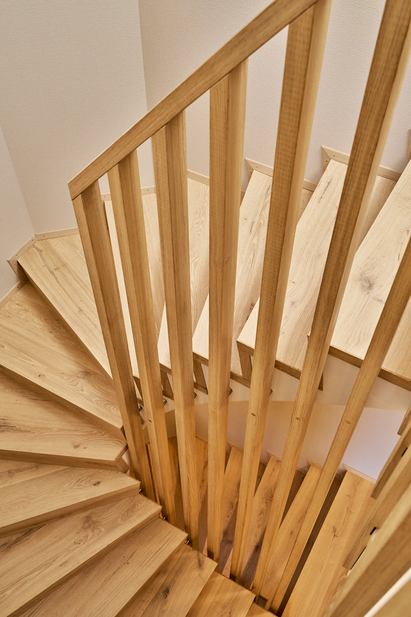 Moderne Holztreppe mit geraden Geländerstäben und geschwungenen Stufen