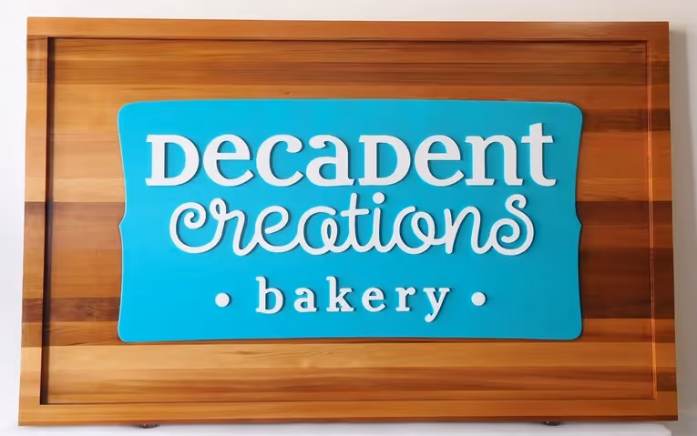 A wooden sign that says decadent creations bakery.