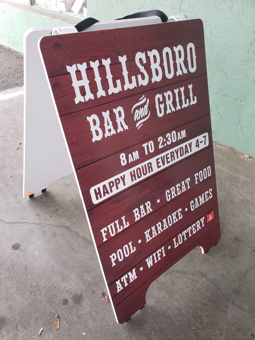 A wooden sign advertising a bar and grill.