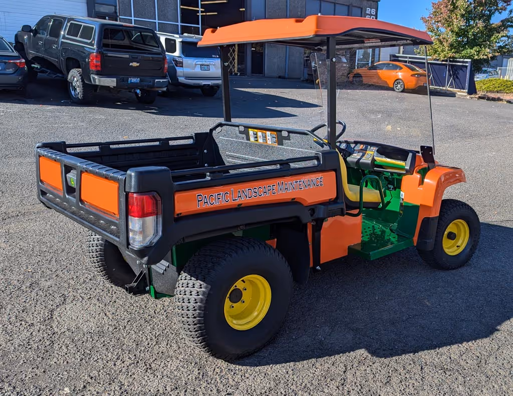 An orange and green utility vehicle parked in a parking lot.