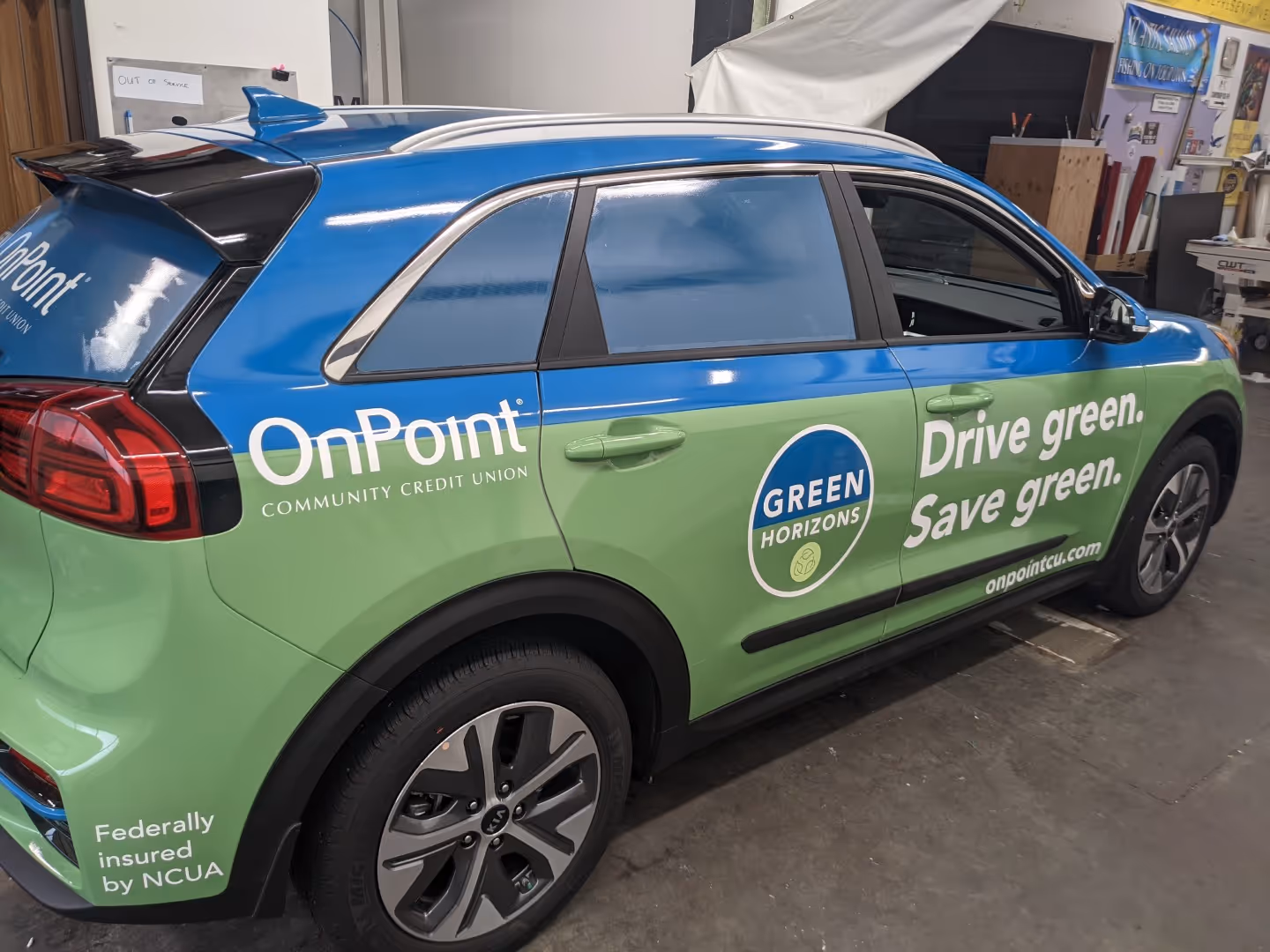 A green and blue car parked in a garage.