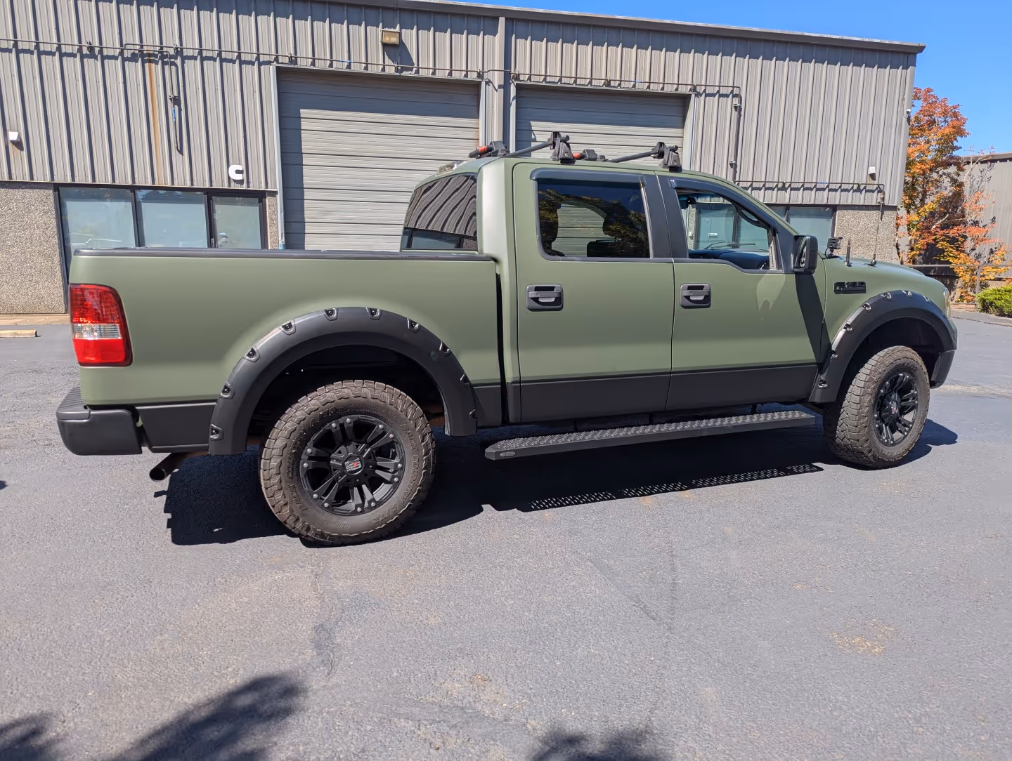 A green truck parked in front of a building.