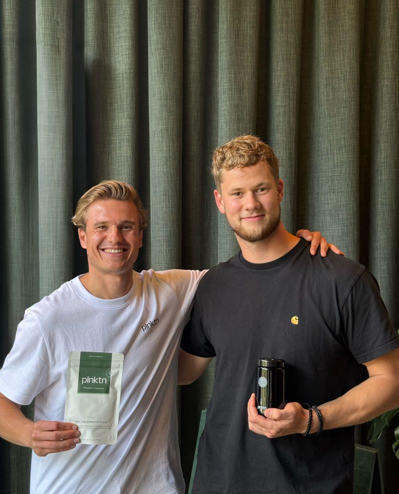 Twee mannen met plnktn producten voor een groen gordijn