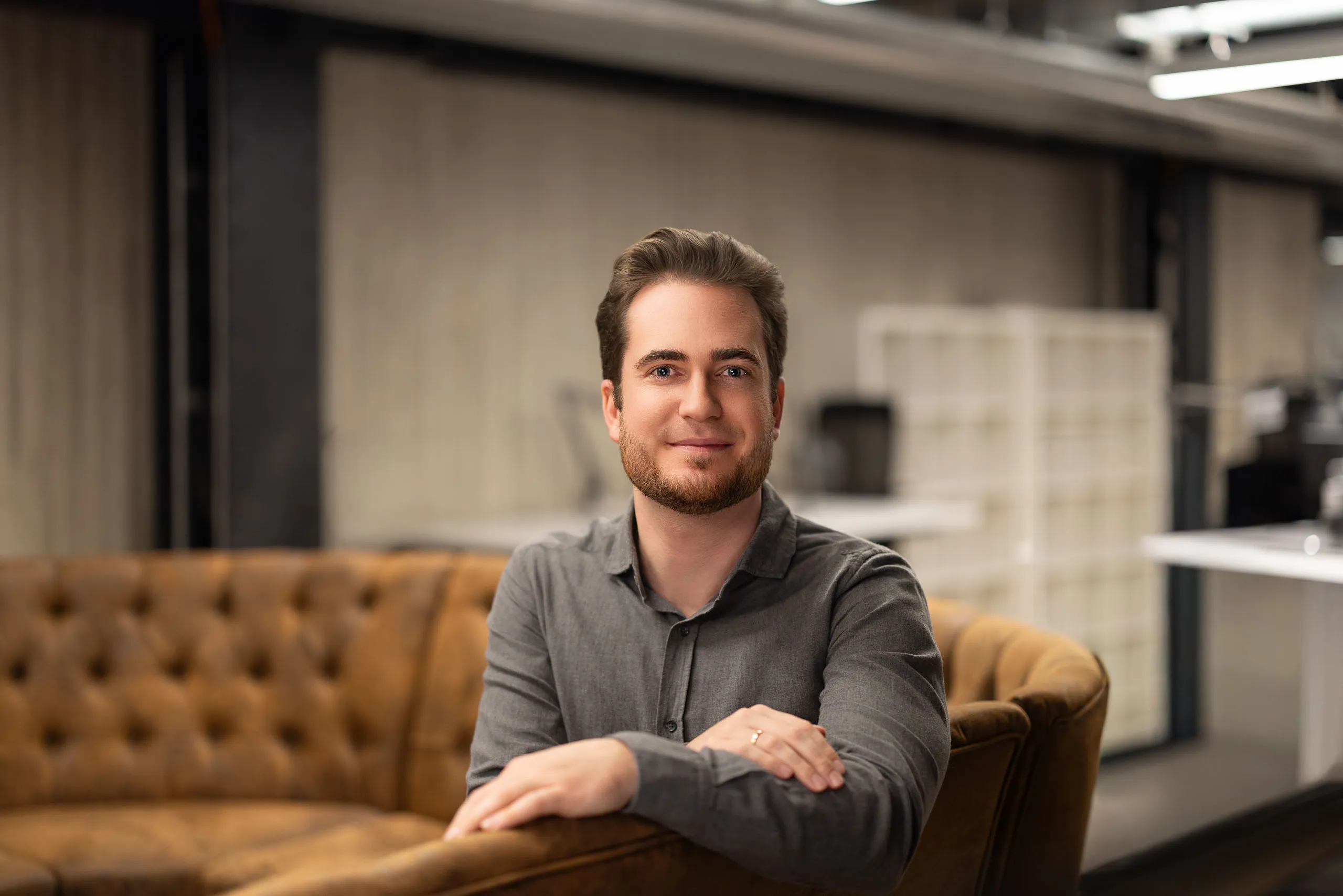 Group of six young adults gathered around a laptop, focused on the screen during a collaborative work session.