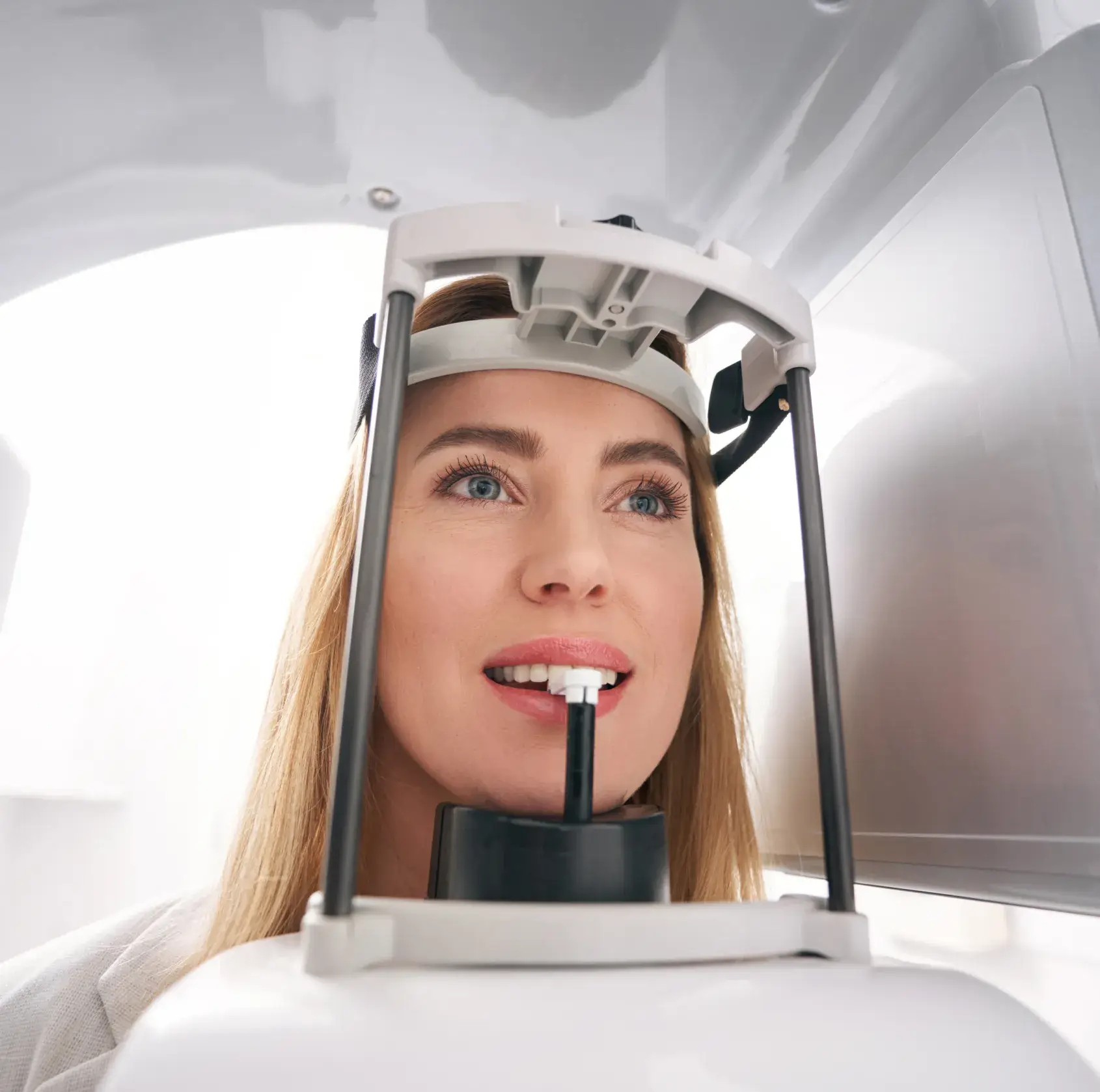 A woman sits in a dental examination chair, preparing for a dental scan.