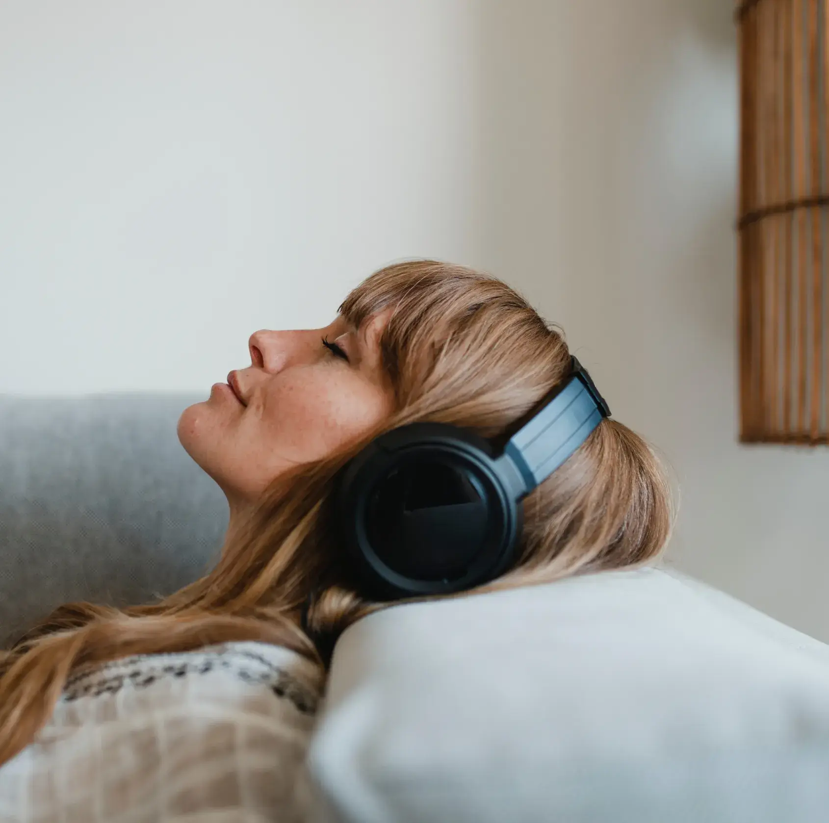 A person is relaxing on a couch, listening to music with large headphones.