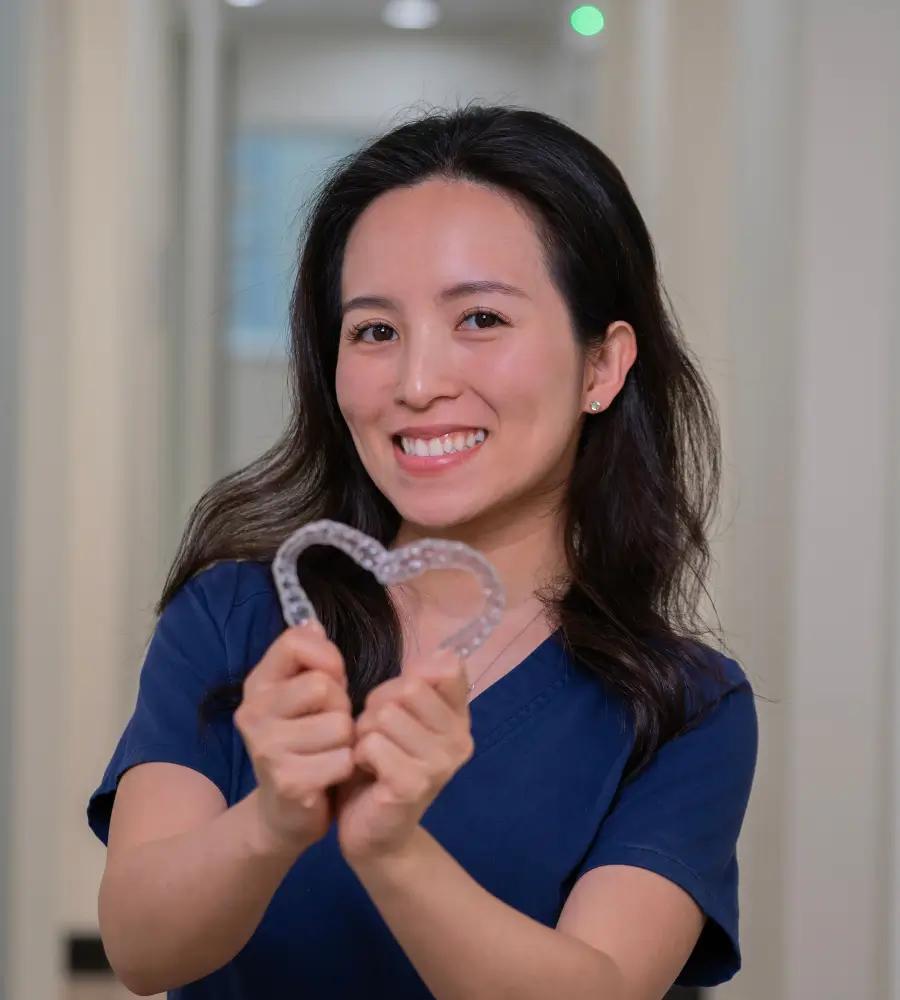 Trusted Dental team member making a heart out of aligners.