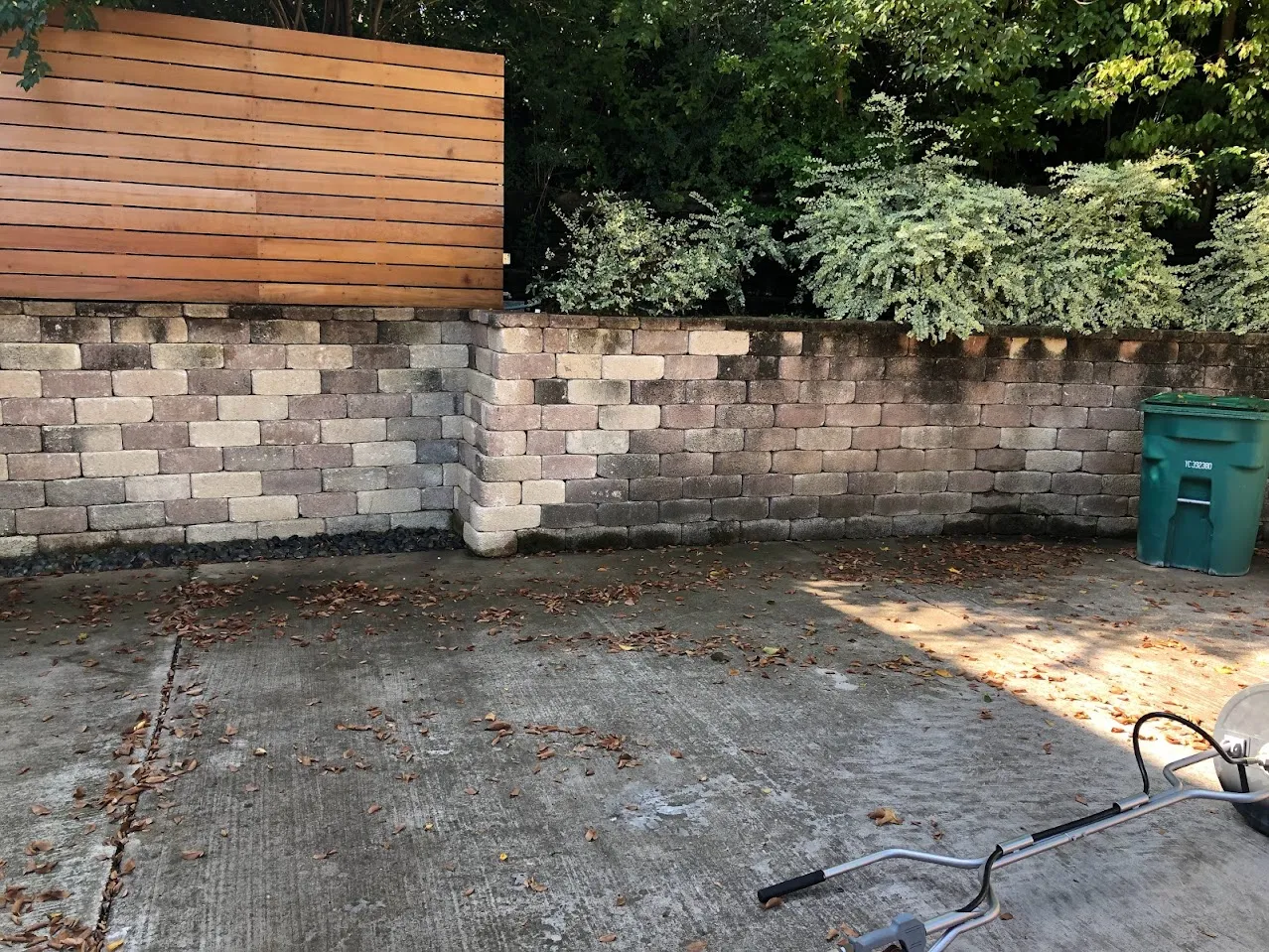 Stained brick retaining wall and concrete driveway before pressure washing