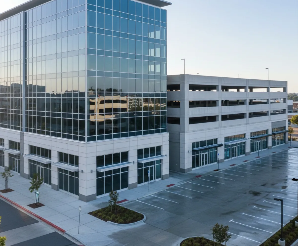 Modern commercial office building with a glass exterior and adjacent parking garage.