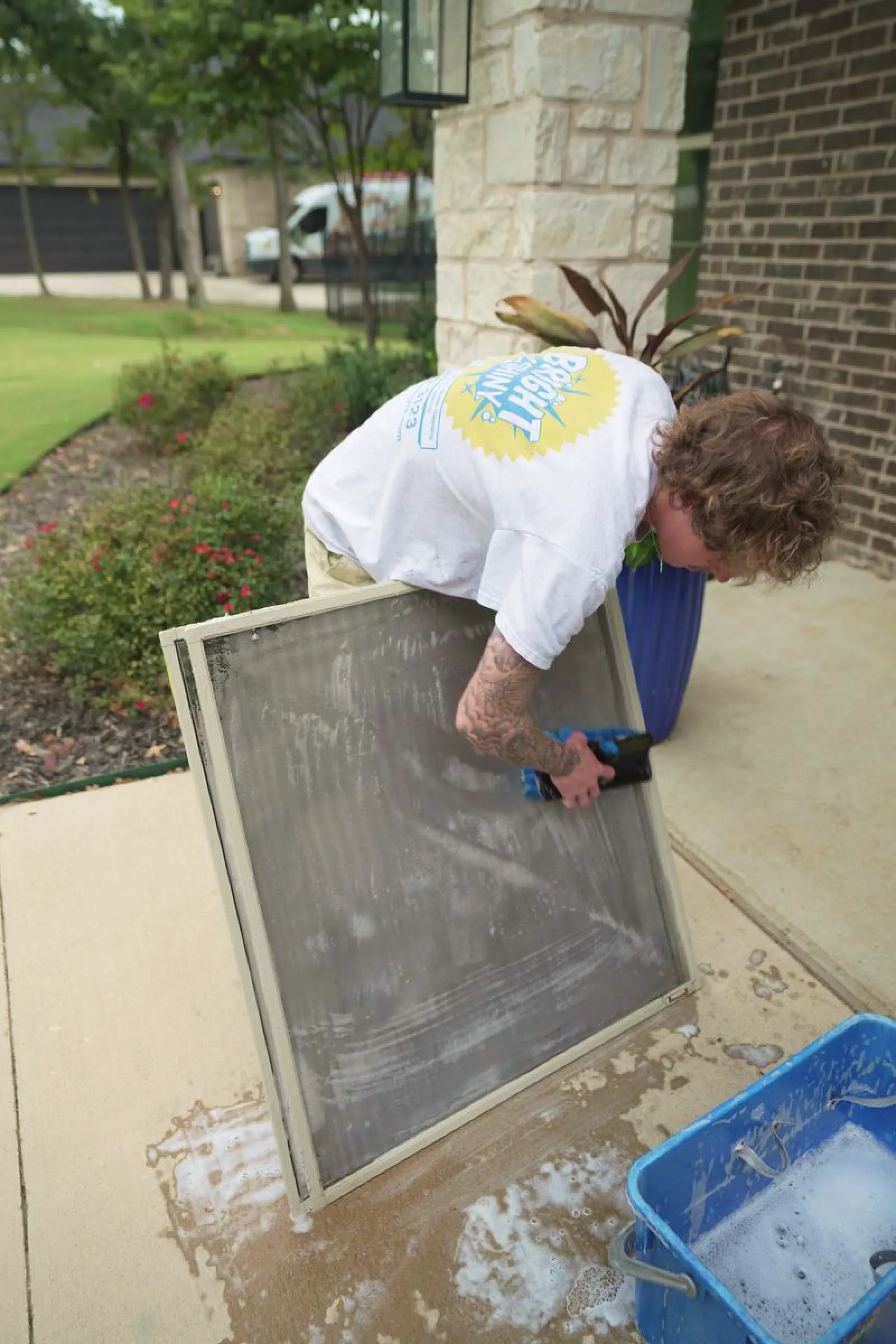 Bright & Shiny technician washing a removed window screen outdoors